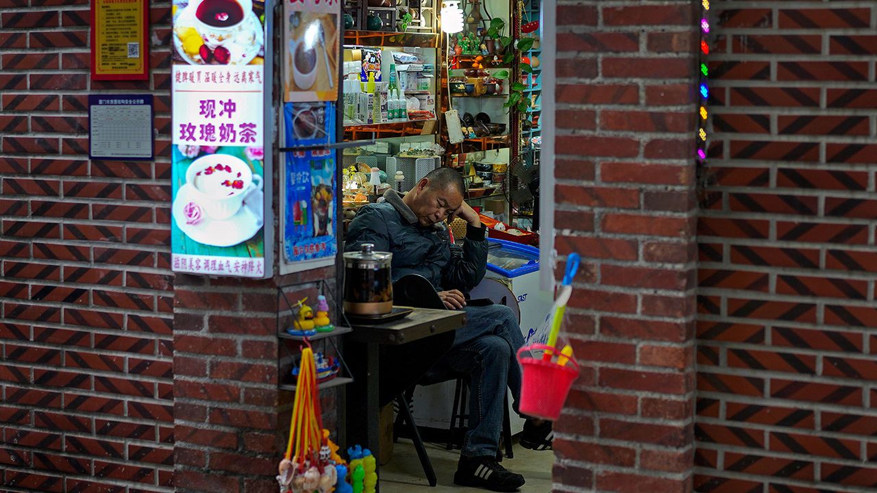 A man browses his smartphone at his store in Xiamen, China