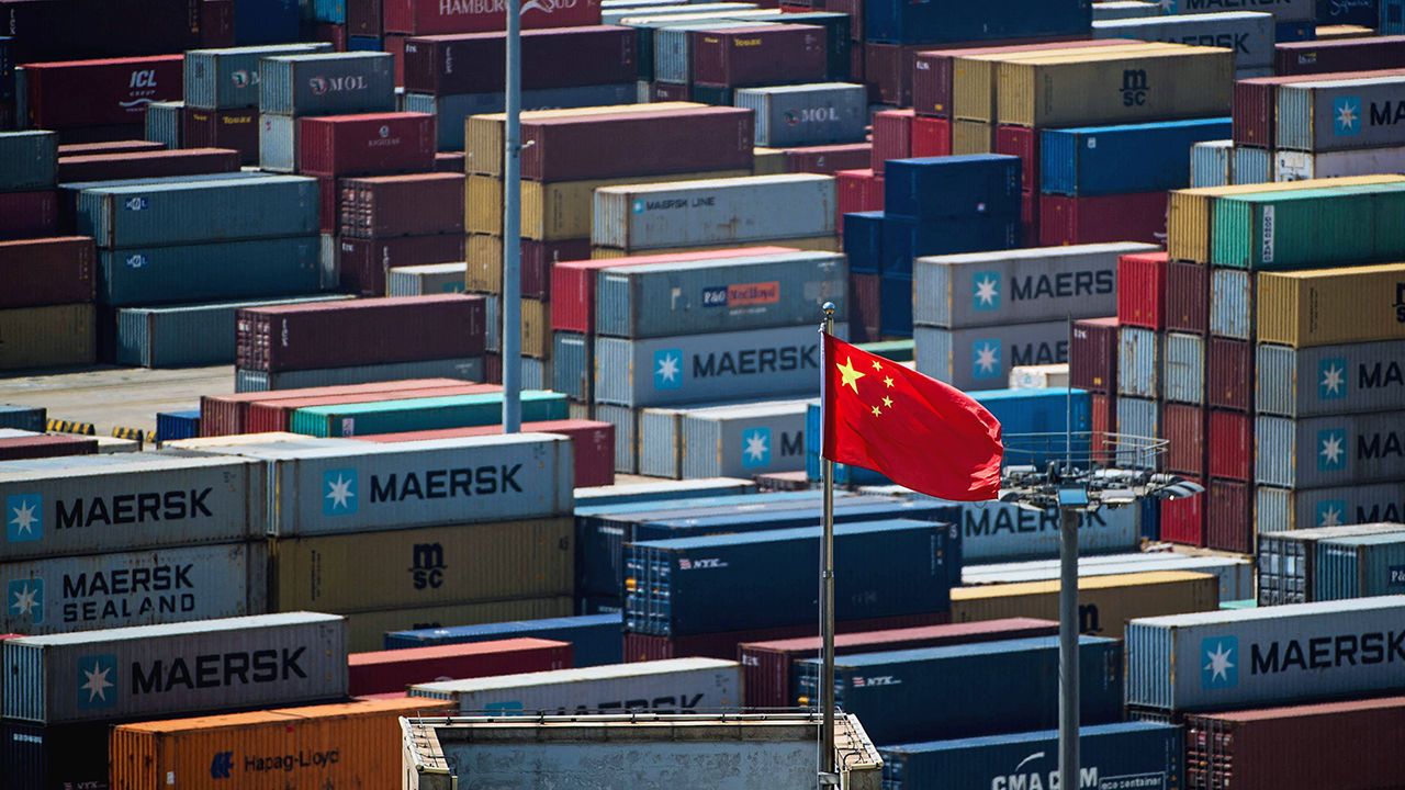 A Chinese flag is seen in front of containers at the Yangshan Deep-Water Port, Shanghai