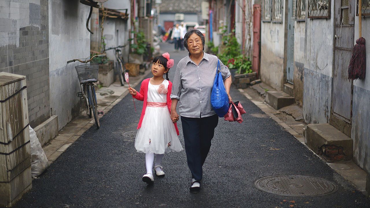 A grandmother walks with her grandchild along an alley in Beijing.