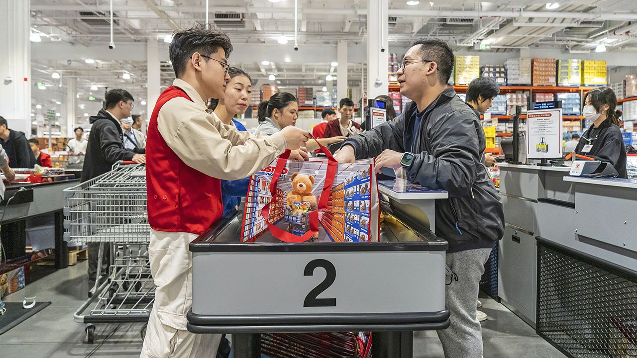 Check-out staff assist a shopper at the Costco Wholesale Corp. store in Shenzhen, China