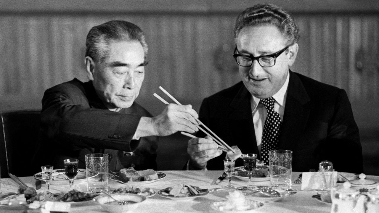 Henry Kissinger accepts food from Zhou Enlai during a state banquet in Beijing